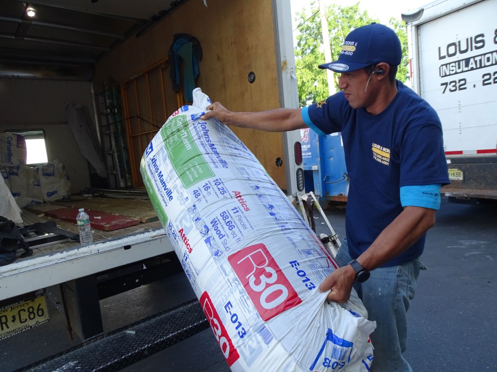 worker loading R-30 insulation into the truck