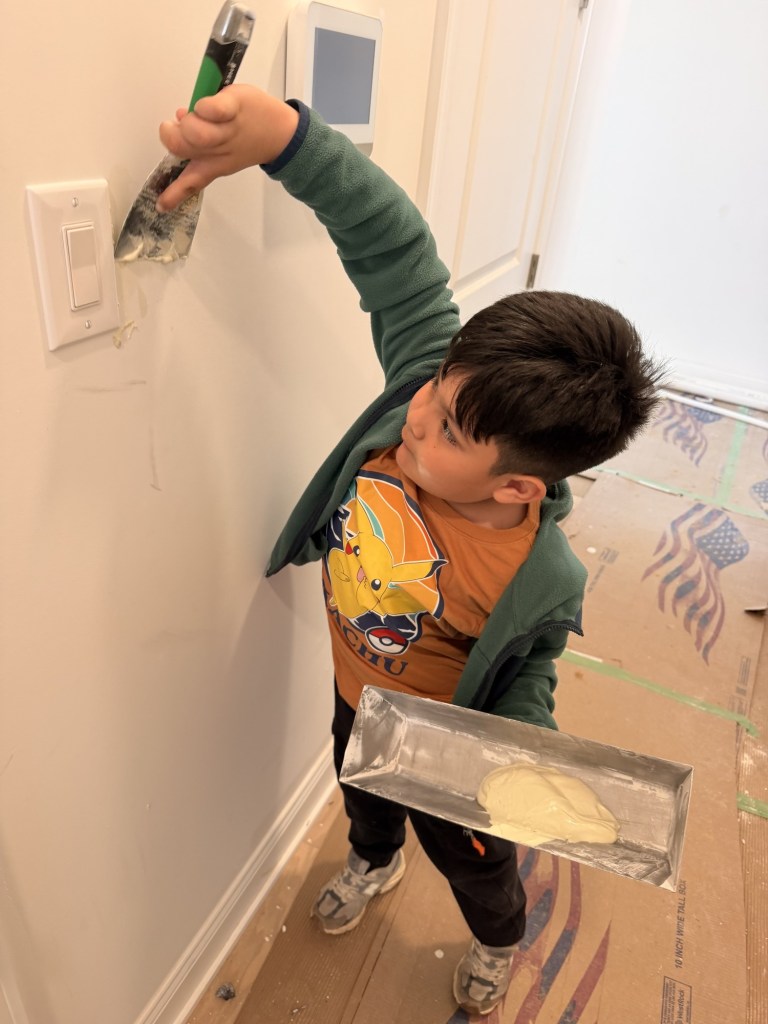 Javier's son spackling near a light switch